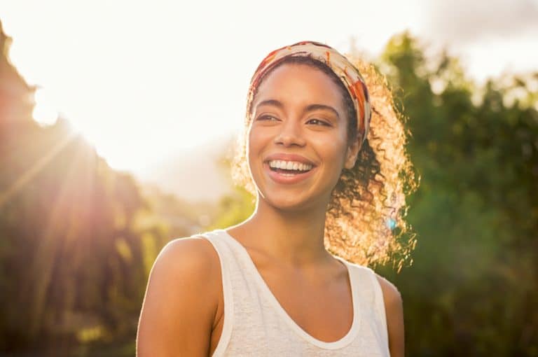 A woman outside smiling and looking to the side